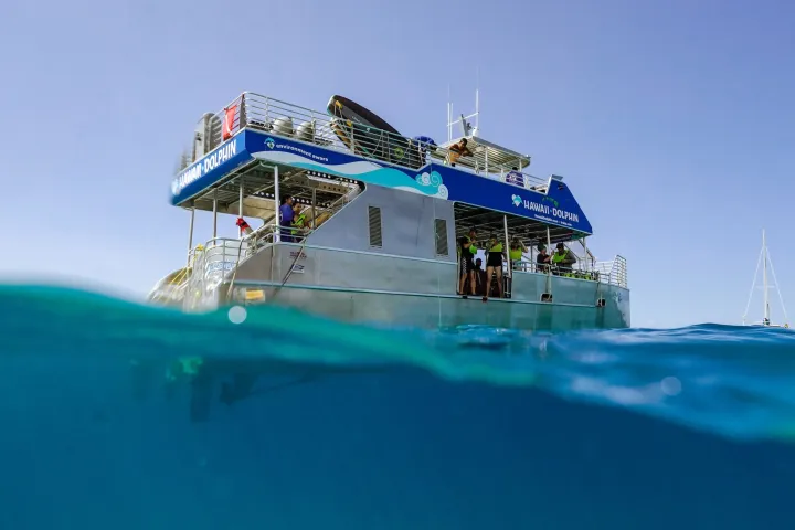 A tour boat on the water with people on board, partially submerged view.