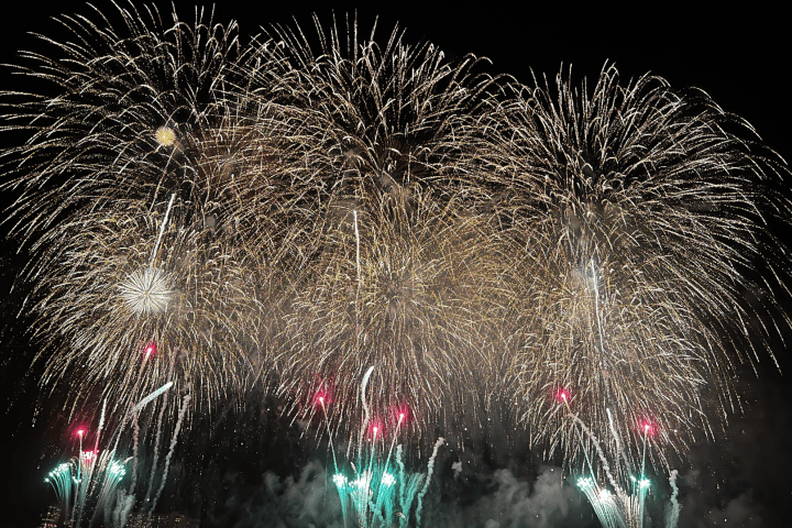 Large bursts of colorful fireworks light up the night sky.