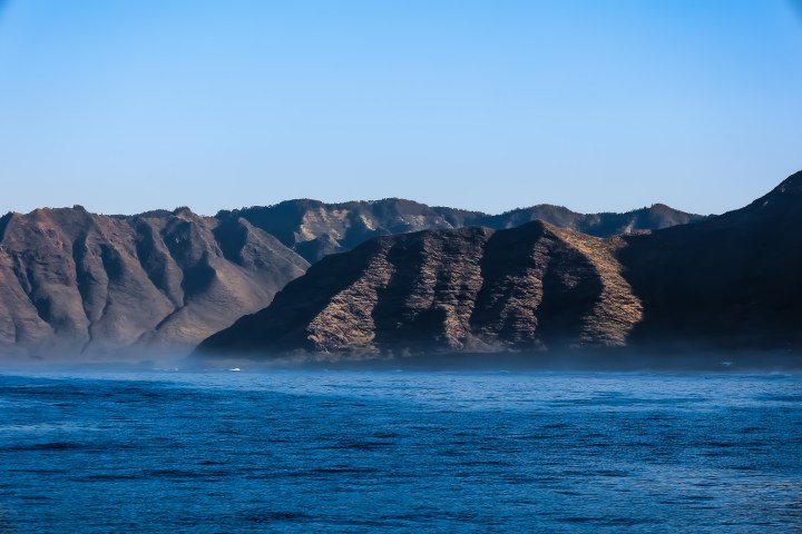a large body of water with a mountain in the background
