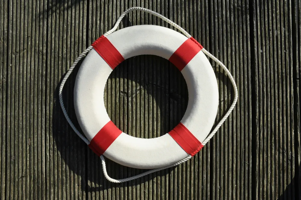 Lifebuoy with red bands on wooden surface.